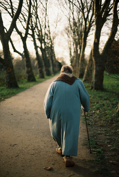 Adulta mayor caminando con bastón en un sendero natural, con estabilidad y confianza